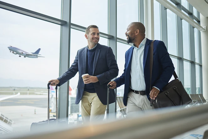dois homens a andar no aeroporto com as suas malas e a conversar