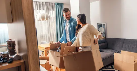 Casal sorridente a desempacotar caixas de mudança na sala de estar