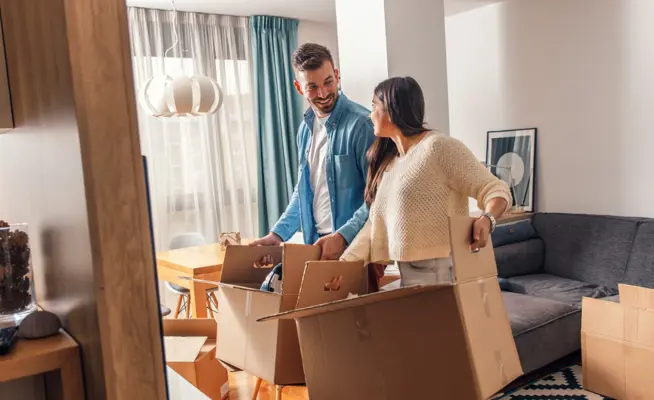 Casal sorridente a desempacotar caixas de mudança na sala de estar