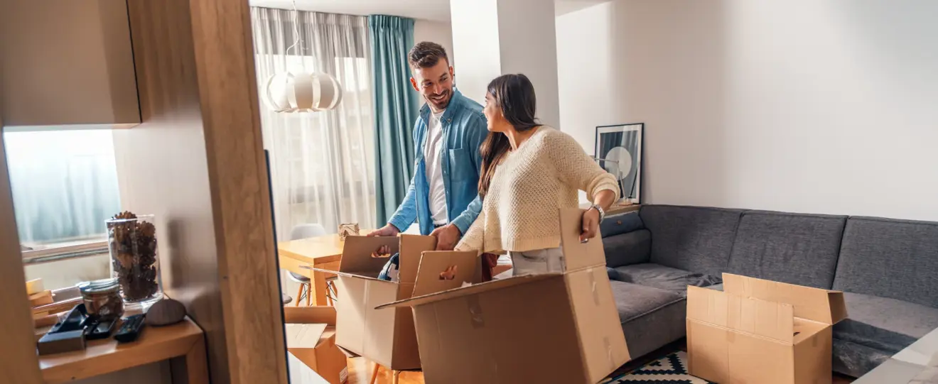 Casal sorridente a desempacotar caixas de mudança na sala de estar
