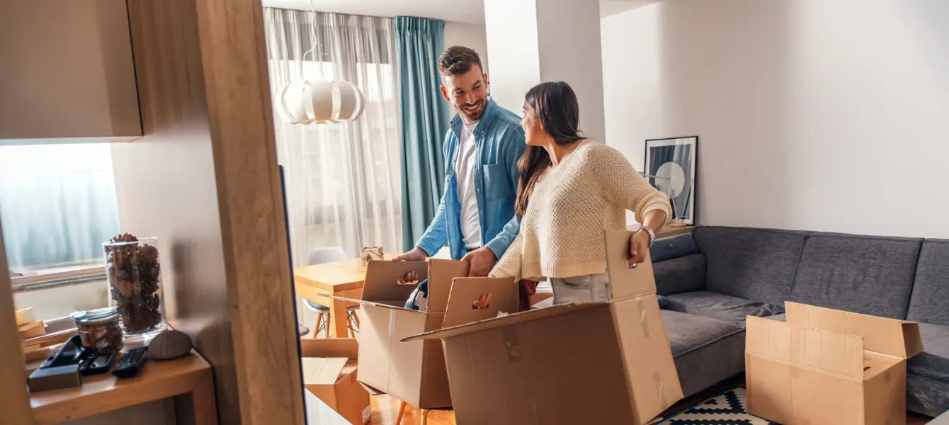 Casal sorridente a desempacotar caixas de mudança na sala de estar
