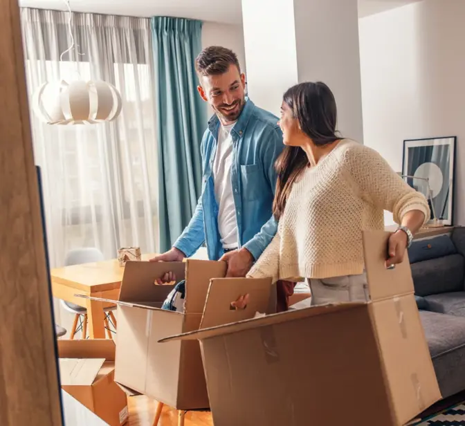 Casal sorridente a desempacotar caixas de mudança na sala de estar
