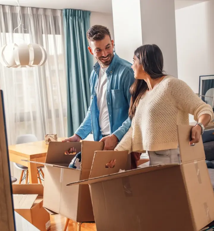 Casal sorridente a desempacotar caixas de mudança na sala de estar