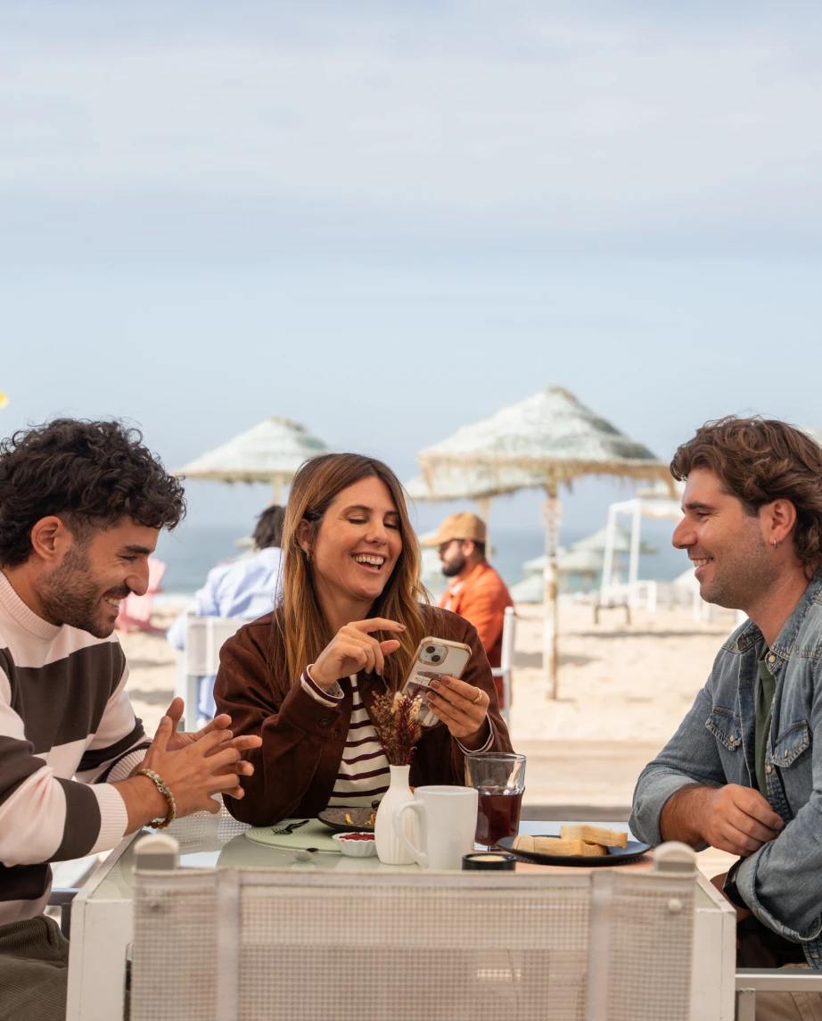 José Condessa e mais dois atores, a representar as personagens Sara Guimarães e Filipe Ribeiro, a conversarem num bar de praia