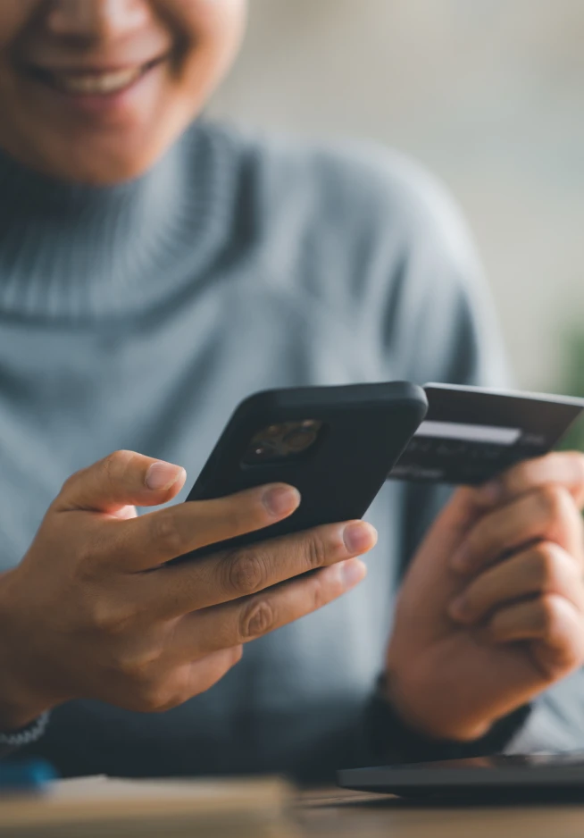 Rapariga a pagar num telemóvel com cartão de crédito