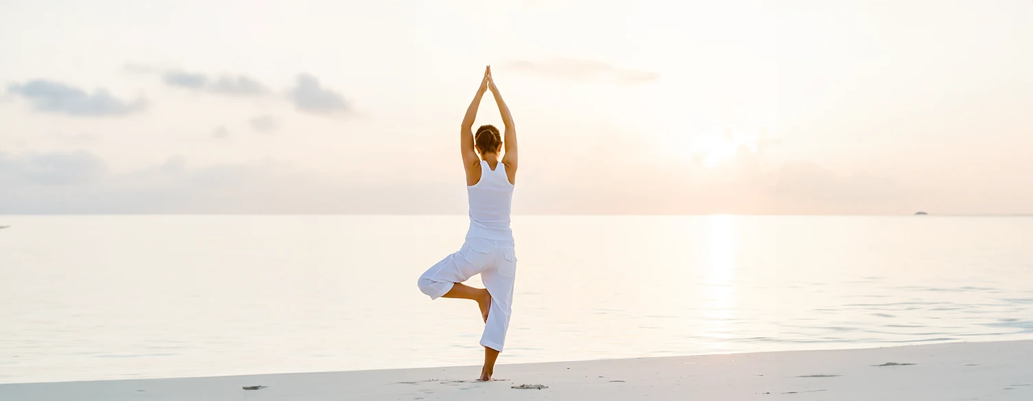 Mulher a fazer yoga na praia, ao pôr do sol