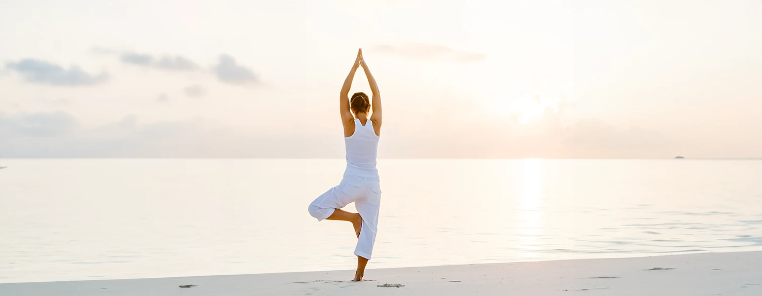 woman doing yoga on the beach at sunset