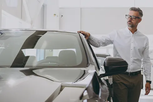 homem, num stand, a tocar num carro novo