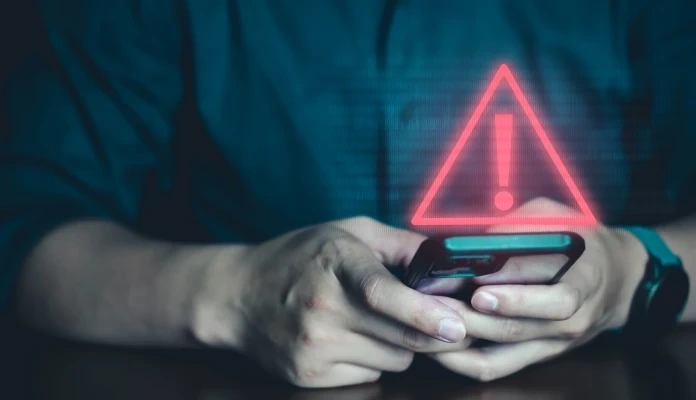 Pessoa a usar telemóvel com um símbolo de alerta de segurança vermelho