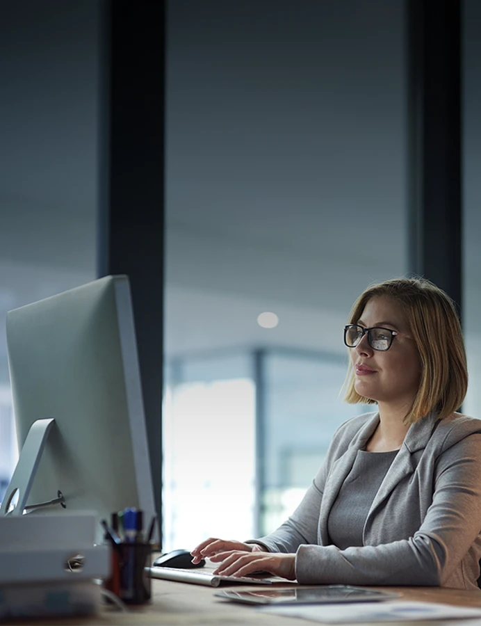 senhora sentada, a trabalhar num computador, num escritório