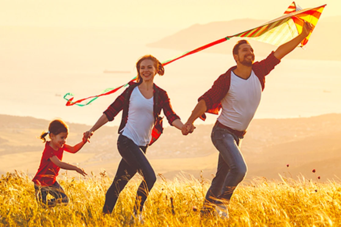 young couple with a girl walking in the countryside, holding a paper kite