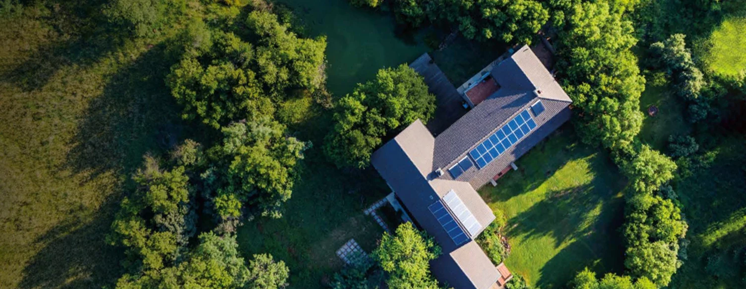 house with solar panels in the middle of a green field