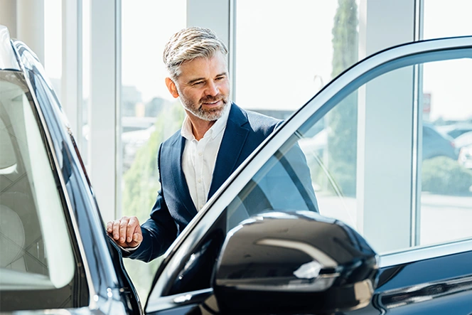 homem de blazer azul, a entrar em carro novo