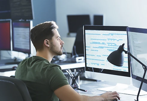 Homem sentado numa secretária e a usar o teclado de um computador