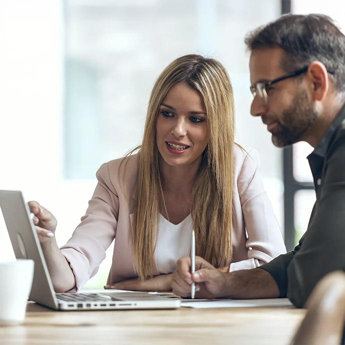 homem e mulher em frente a computador, ela a apontar para o monitor