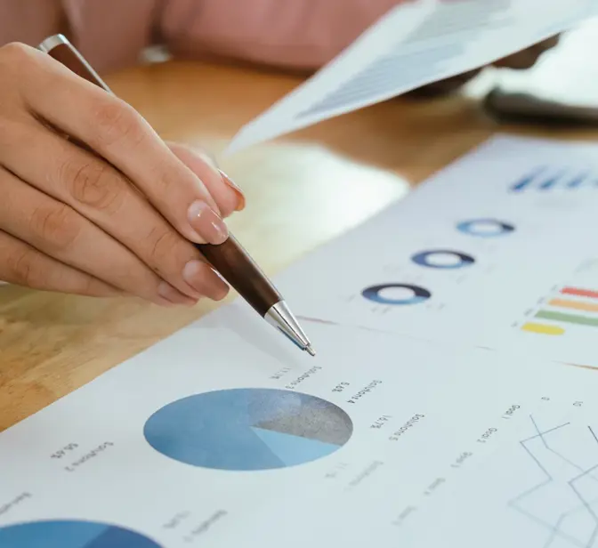 Mão a apontar para um gráfico circular em documentos de análise financeira