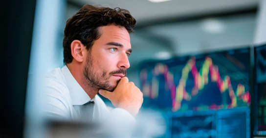 Homem analisa gráficos de mercados financeiros em monitores