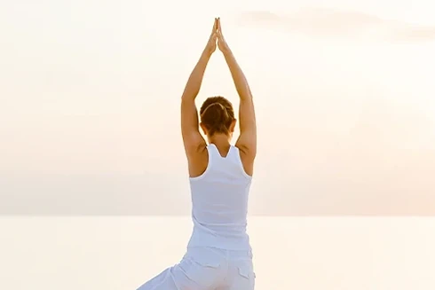 Mulher a fazer yoga na praia, ao pôr do sol