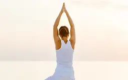 Mulher a fazer yoga na praia, ao pôr do sol