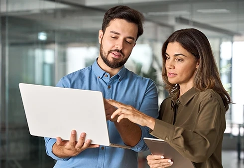Homem e mulher a olhar para um ecrã de portátil num escritório