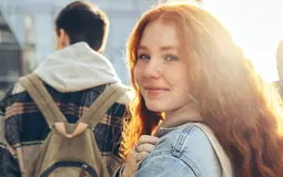 rapariga, estudante, a caminhar na rua com saco ao ombro