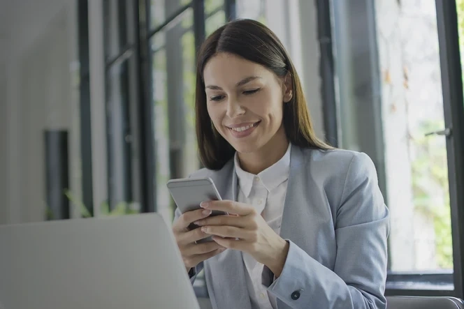 Smiling woman using her mobile phone in an office