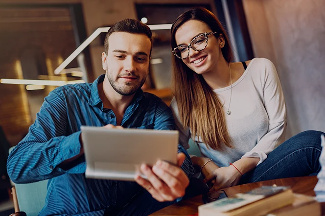 Casal sentado numa mesa de café, a mexer num tablet