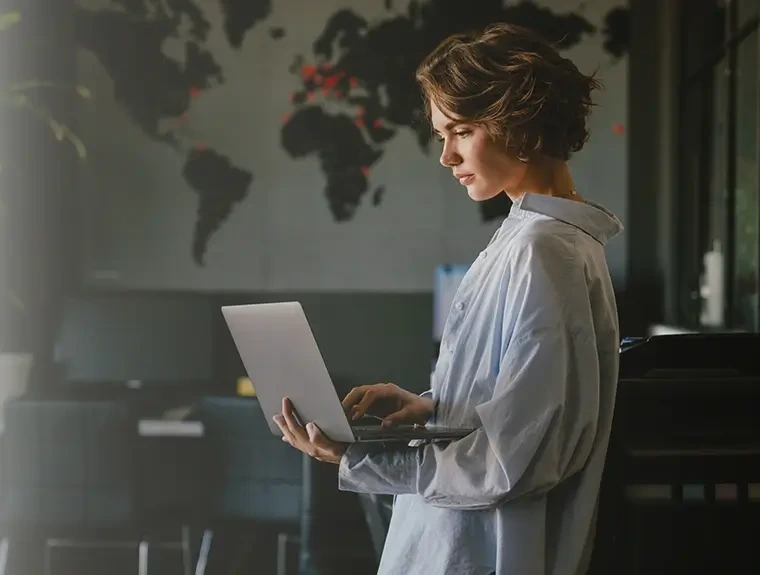 senhora em pé, com computador portátil aberto na mão