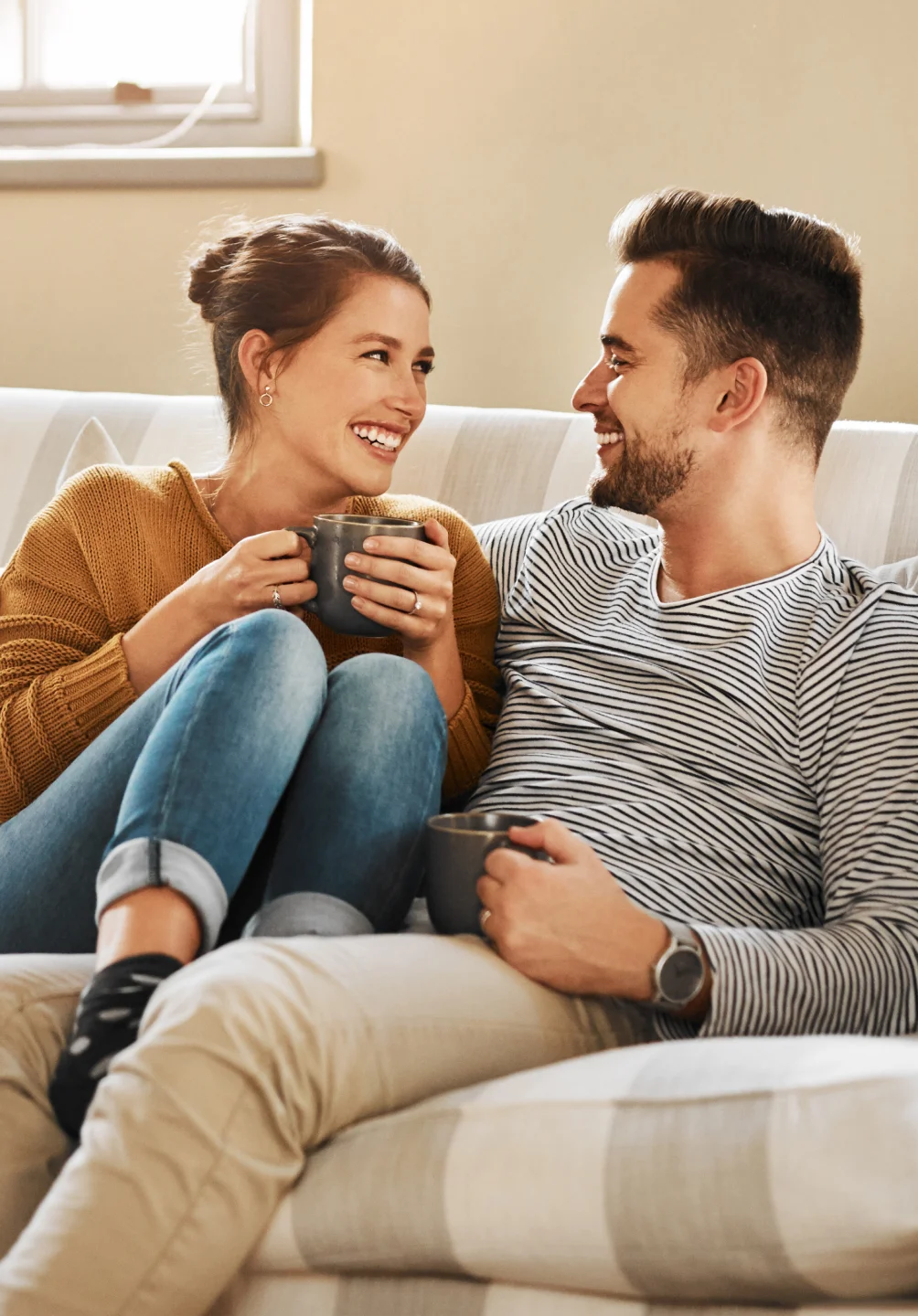 Casal no sofá sorridente com uma chávena de café