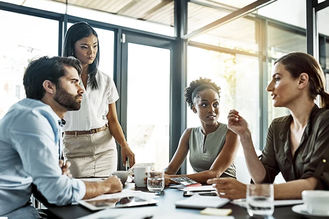 Grupo de pessoas sentadas à mesa  com chávenas e copos de água e a conversar