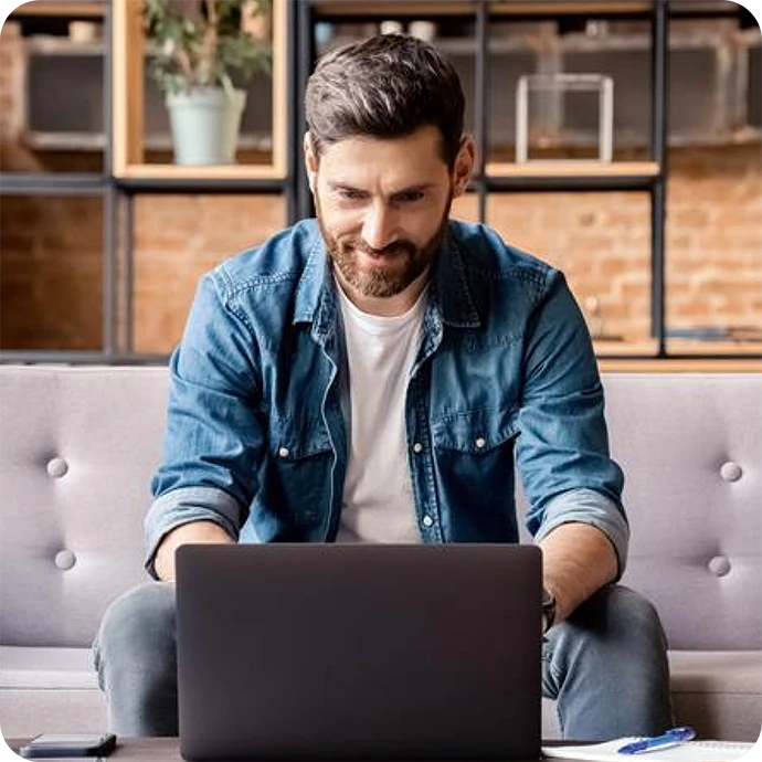 homem sentado no sofá a trabalhar num computador portátil