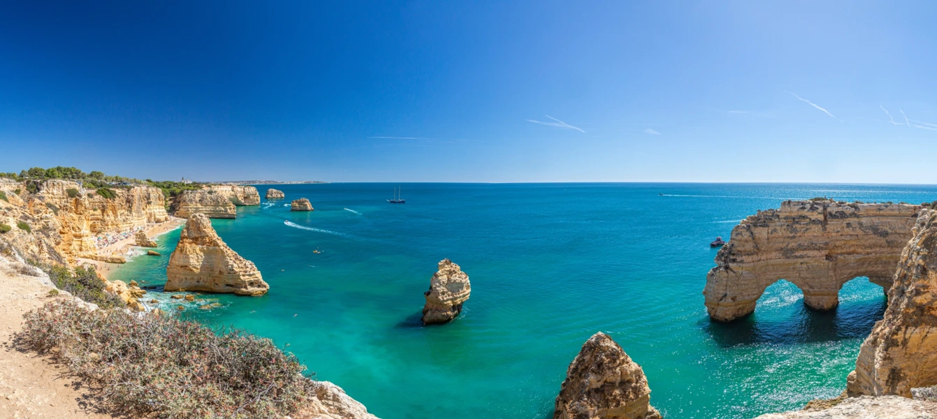 Vista panorâmica da costa do Algarve com falésias douradas, arcos rochosos e mar azul-turquesa