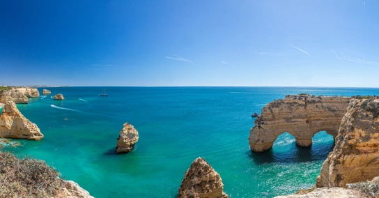 Vista panorâmica da costa do Algarve com falésias douradas, arcos rochosos e mar azul-turquesa