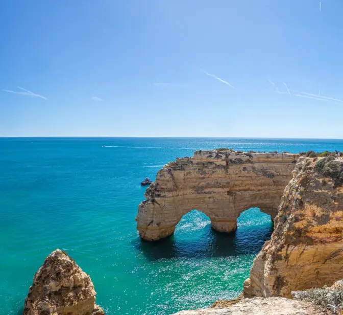 Vista panorâmica da costa do Algarve com falésias douradas, arcos rochosos e mar azul-turquesa