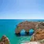 Vista panorâmica da costa do Algarve com falésias douradas, arcos rochosos e mar azul-turquesa