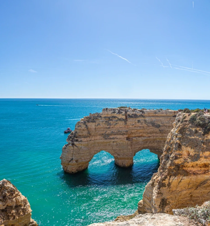 Vista panorâmica da costa do Algarve com falésias douradas, arcos rochosos e mar azul-turquesa