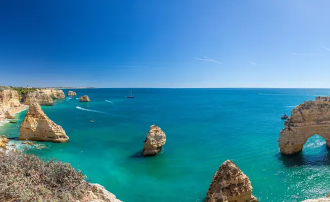 Vista panorâmica da costa do Algarve com falésias douradas, arcos rochosos e mar azul-turquesa