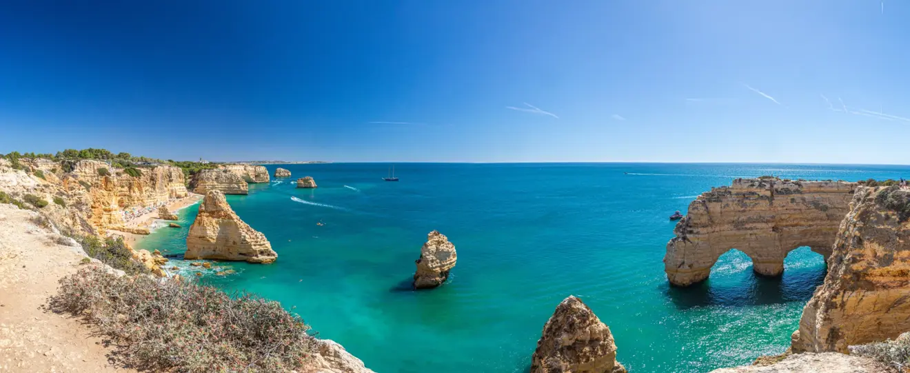Vista panorâmica da costa do Algarve com falésias douradas, arcos rochosos e mar azul-turquesa