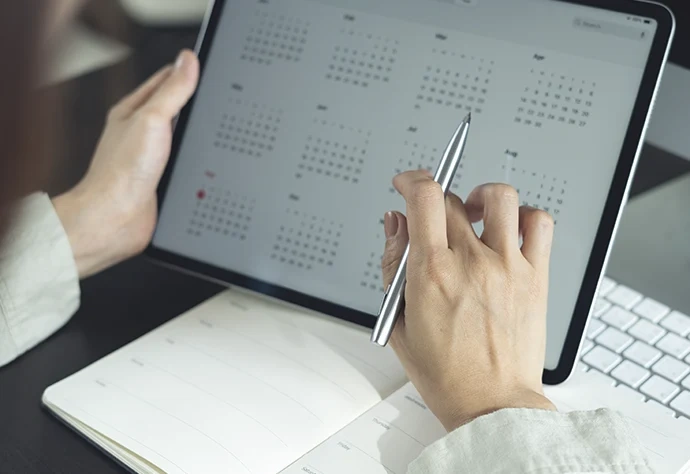 Pessoa a consultar um calendário digital num tablet com uma caneta