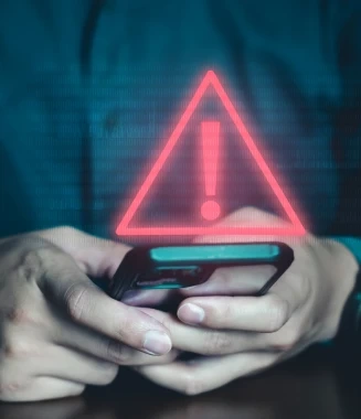 Pessoa a usar telemóvel com um símbolo de alerta de segurança vermelho