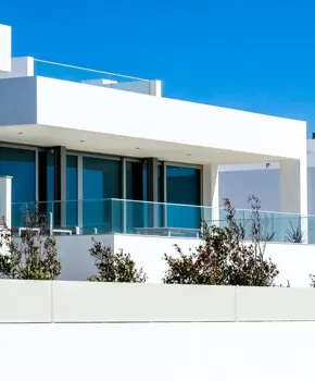 Casas modernas brancas com grandes janelas e varandas sob céu azul