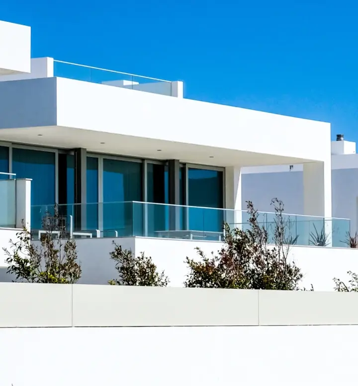 Casas modernas brancas com grandes janelas e varandas sob céu azul