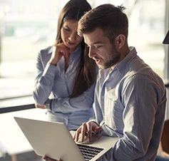 mulher e homem com laptop, a conversar e olhar para o ecrã