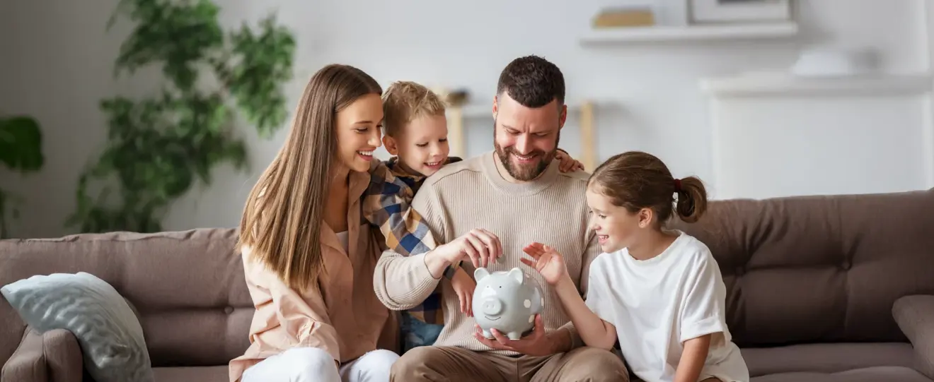 Família a colocar moedas num mealheiro cinzento no sofá
