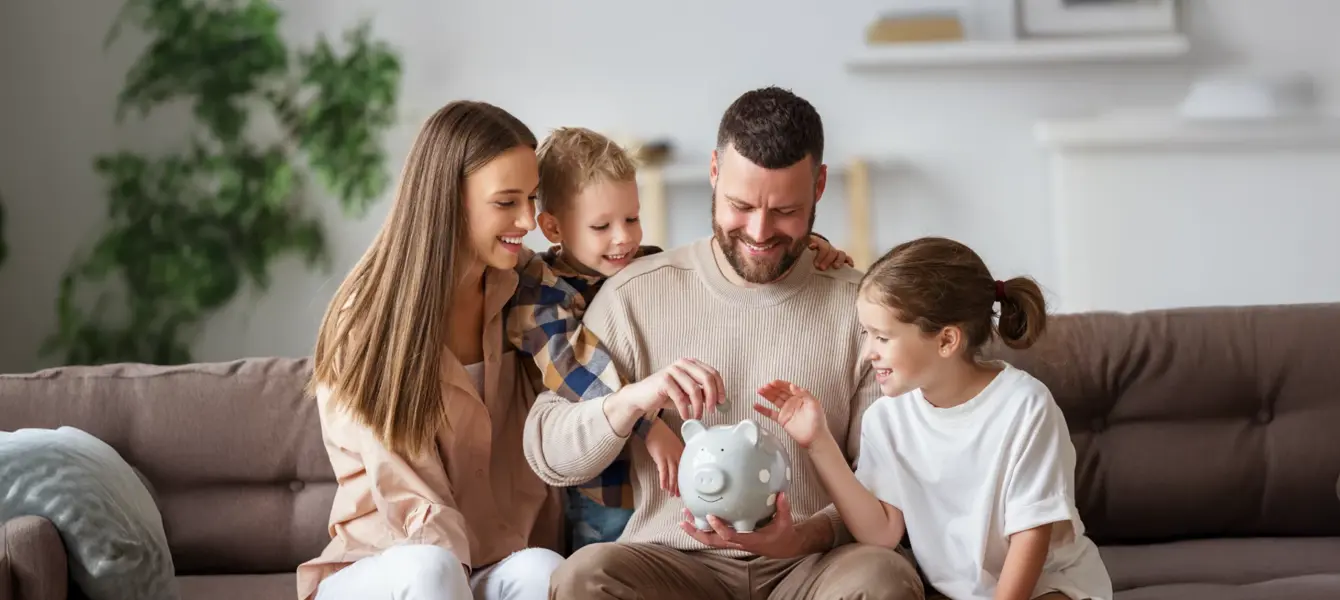 Família a colocar moedas num mealheiro cinzento no sofá
