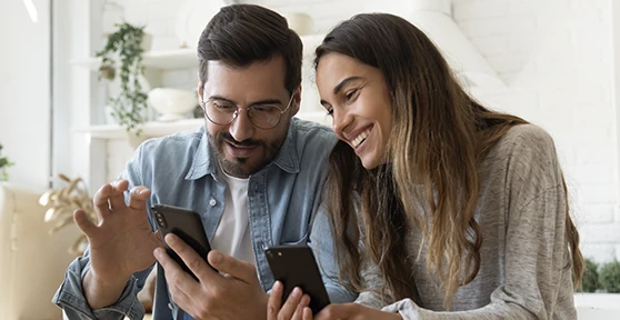casal sorridente, mostrando telemóveis um ao outro