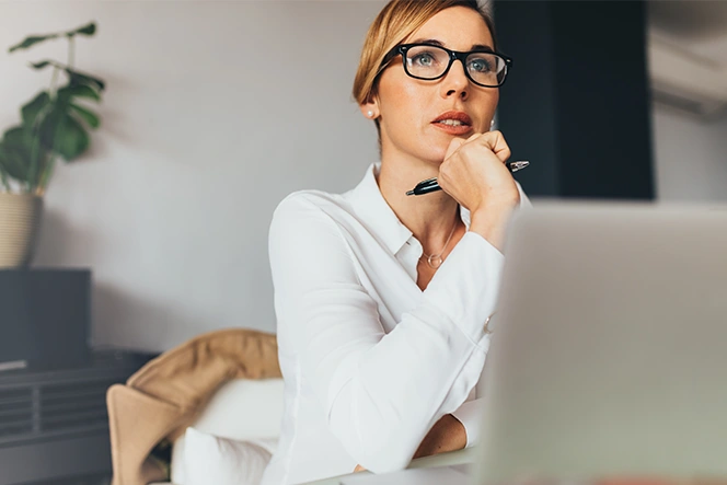 senhora com ar pensativo, em frente ao computador