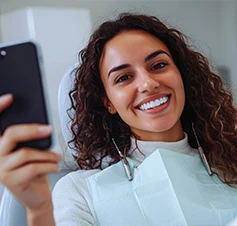 senhora sorridente no dentista, a tirar selfie com telemóvel