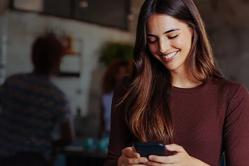 woman smilling while looking at her phone