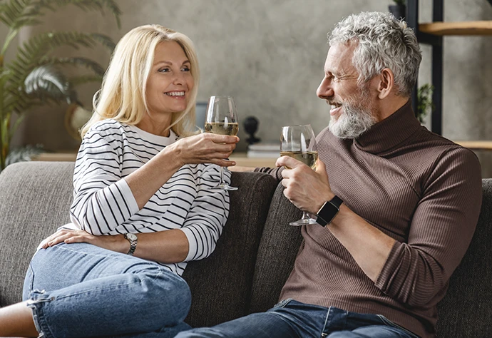 casal maduro no sofá com copos de vinho na mão